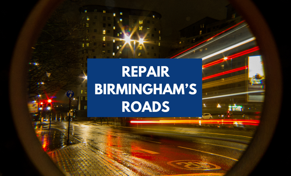 A blurred picture of an open road through a city centre. Text with a blue underlay reads, Repair Birmingham's Roads.