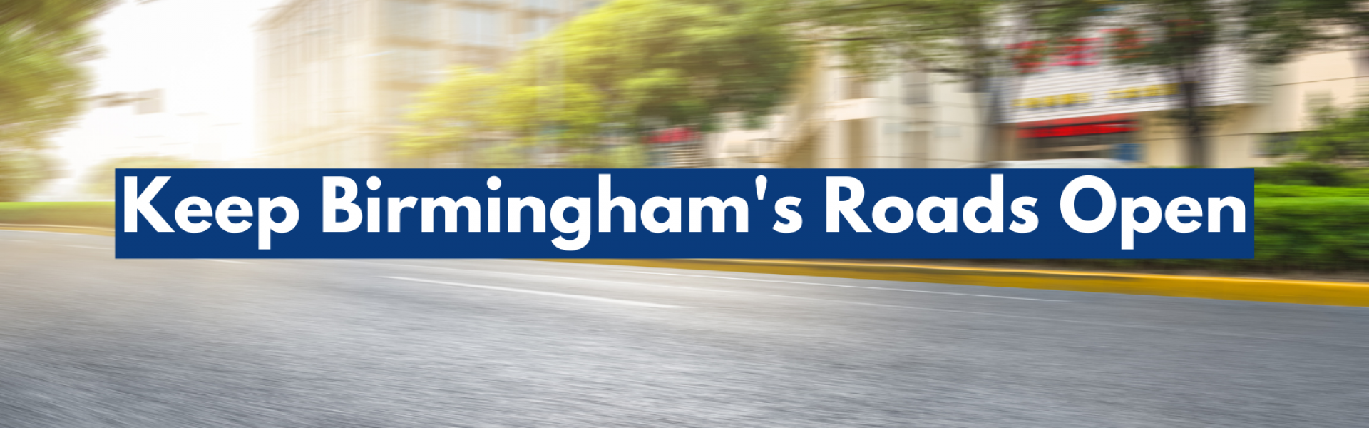 A blurred picture of an open road through a city centre. Text with a blue underlay reads, Keep Birmingham's roads open.