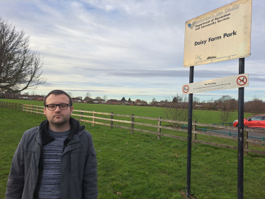Cllr Higgs stood next to the sign for Daisy Farm Park